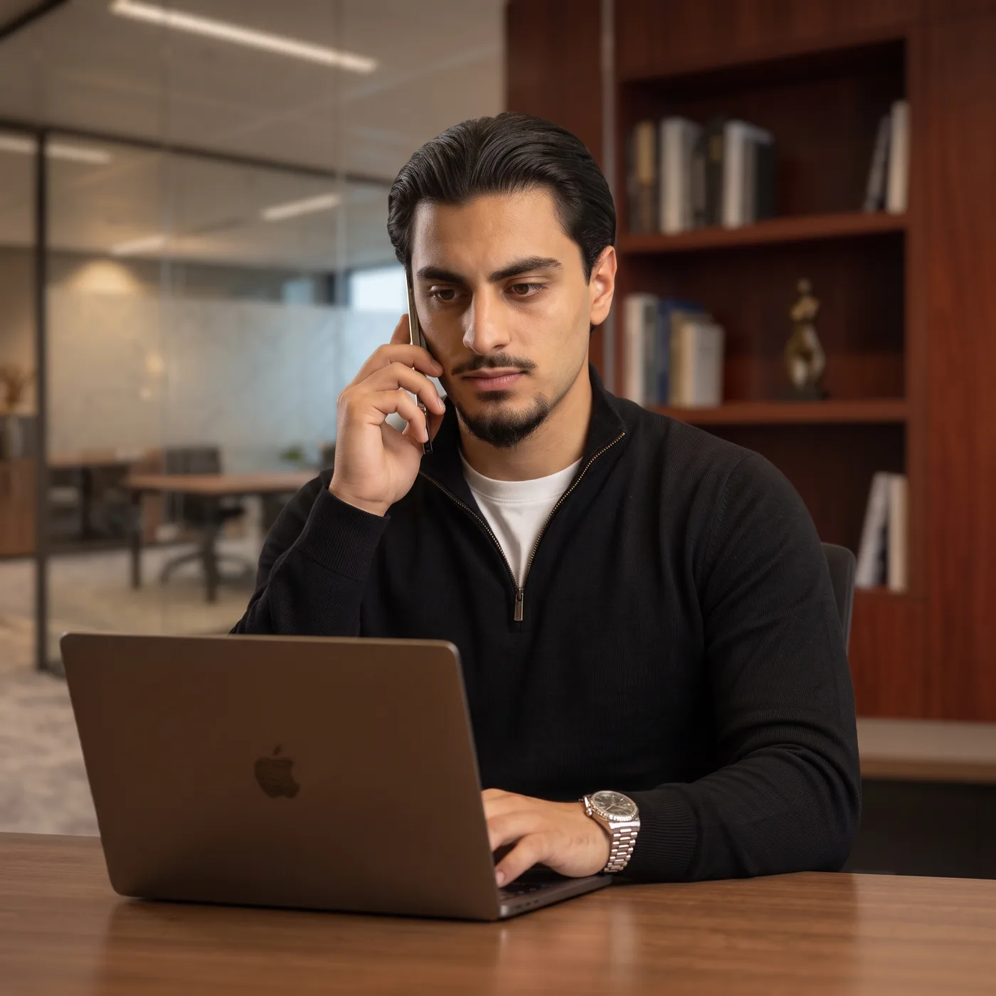 Emraan aan de telefoon achter zijn laptop
